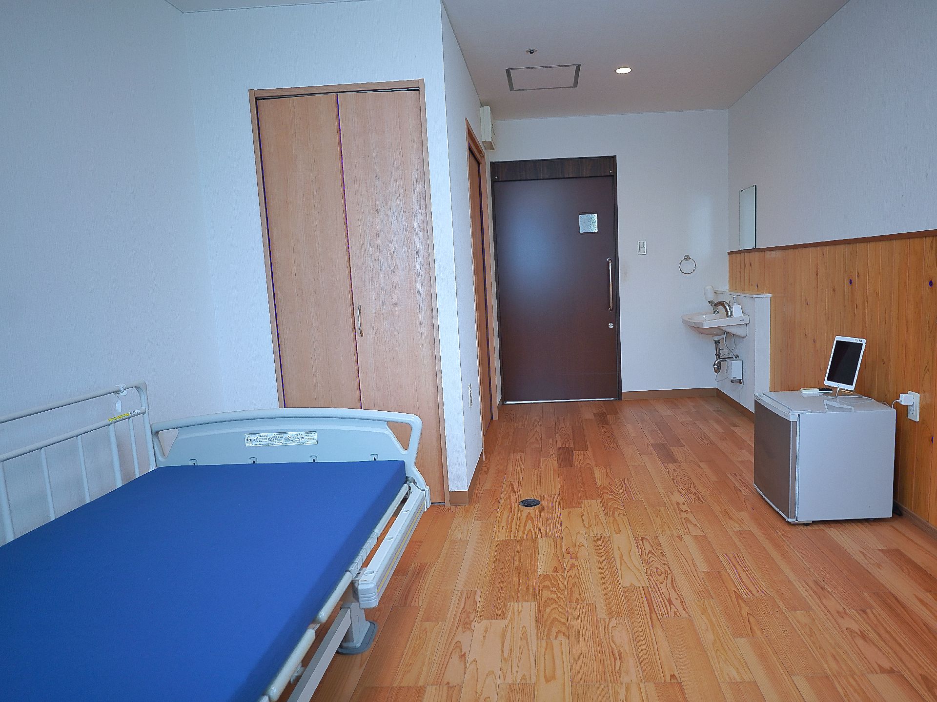 ベッドと洗面台が置かれた白い壁の部屋