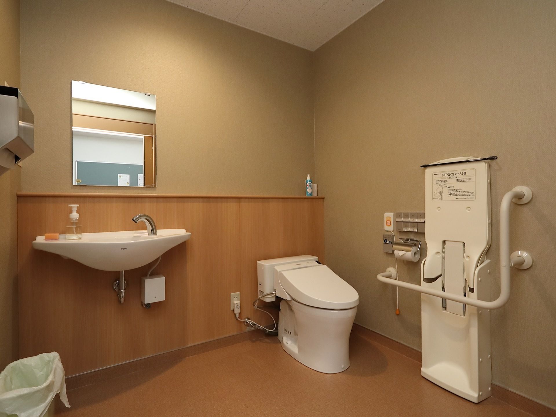 広々とした清潔感のあるトイレには、フットレスタイプの洗面スペースやペーパータオル、手すり、ナースコールが完備されている。