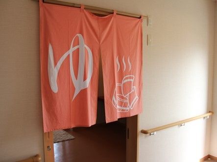 サーモンピンクの暖簾がかかった浴室の出入り口。「ゆ」と大きな文字で書かれている。