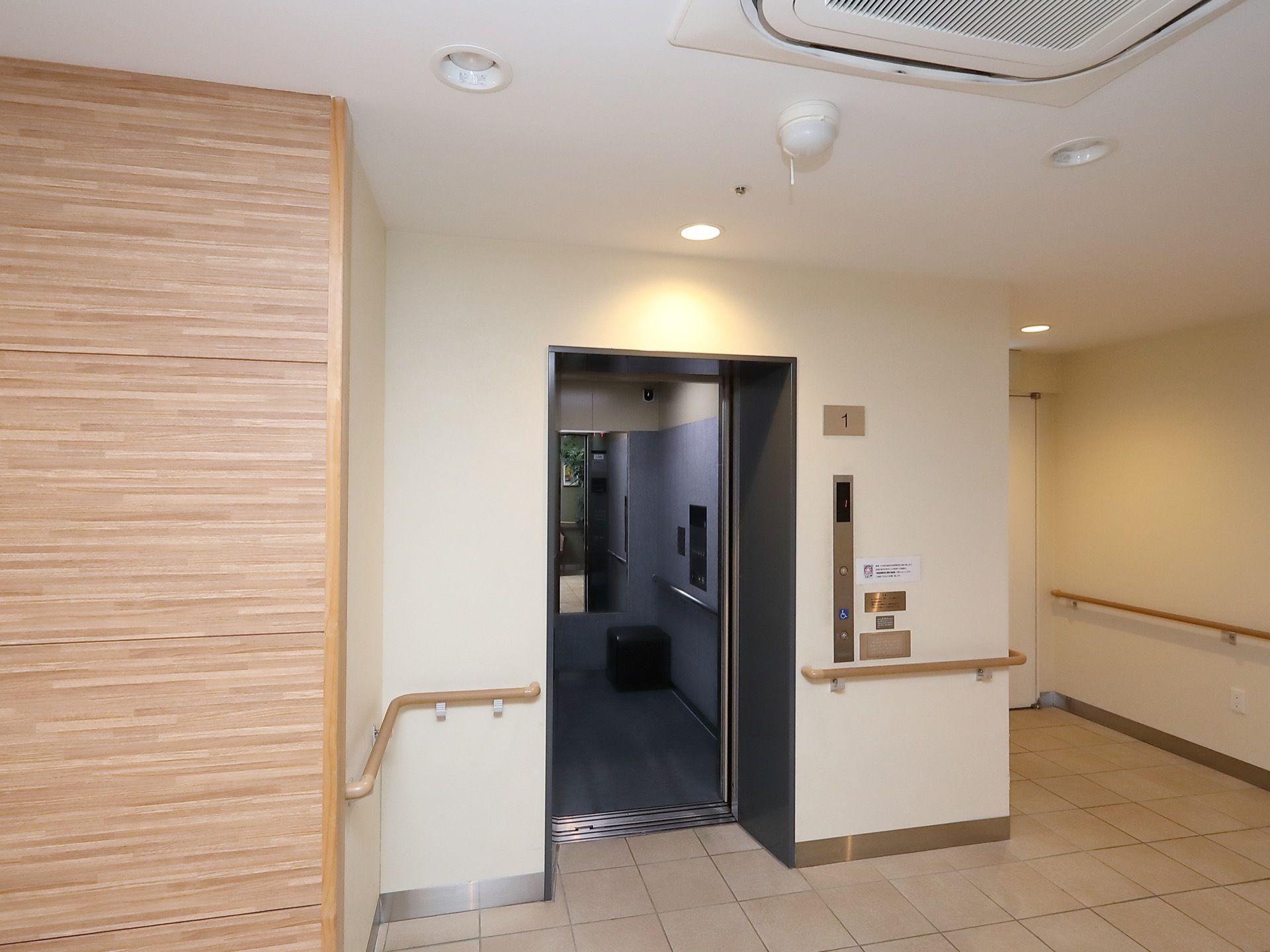 正面にあるエレベーターは扉が開いている。ドアの横の壁には呼出しボタンがあり、その上に階数表示がされている。