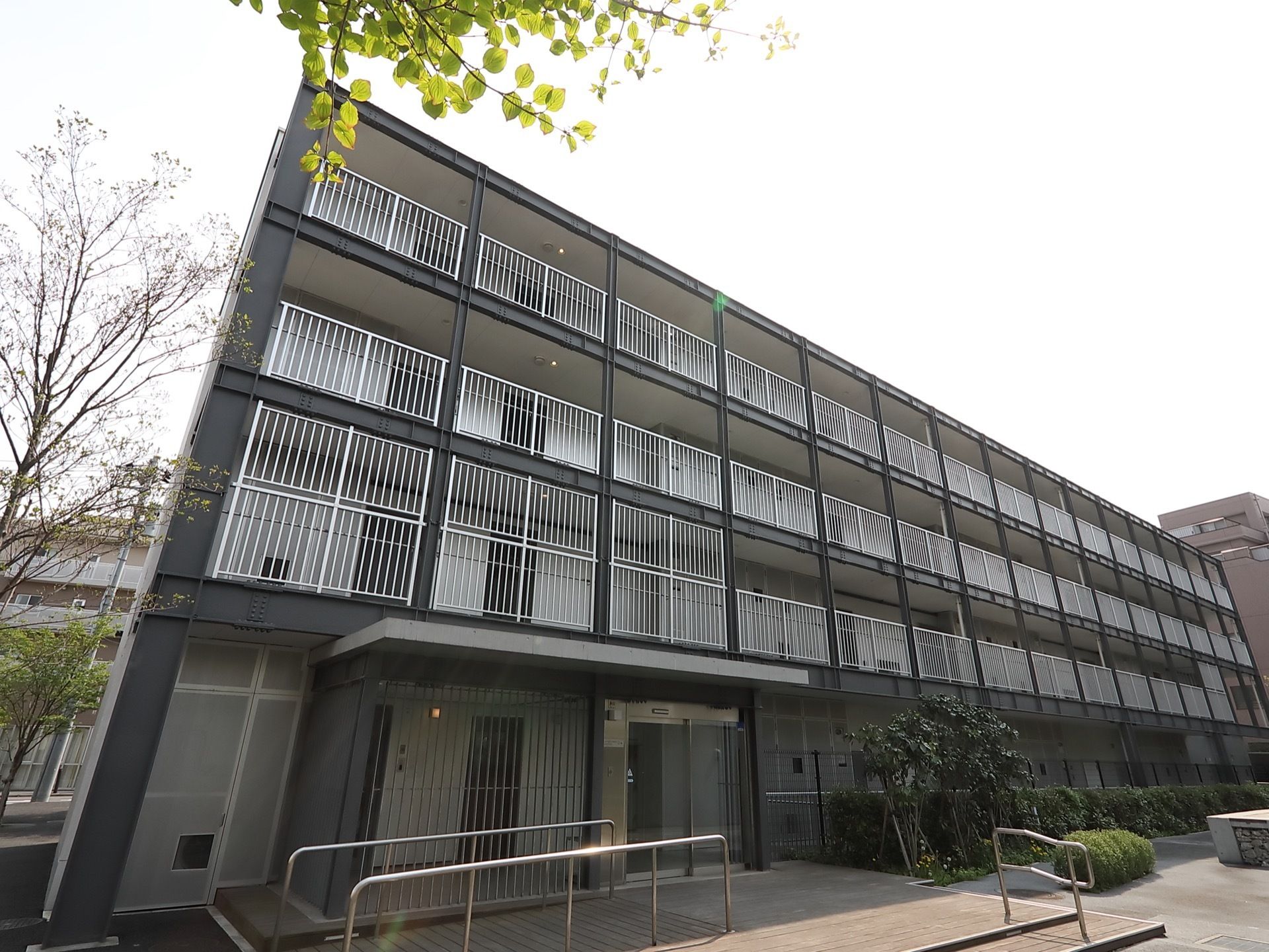 黒と白を基調にした建物で、ベランダの柵は白で統一されている。４階建ての建物で、居室へのドアが並んでいる。