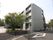 ４階建ての白い外壁の建物で、施設前に道路が通っている。玄関前の敷地には大きな樹木がたくさん植えられている。