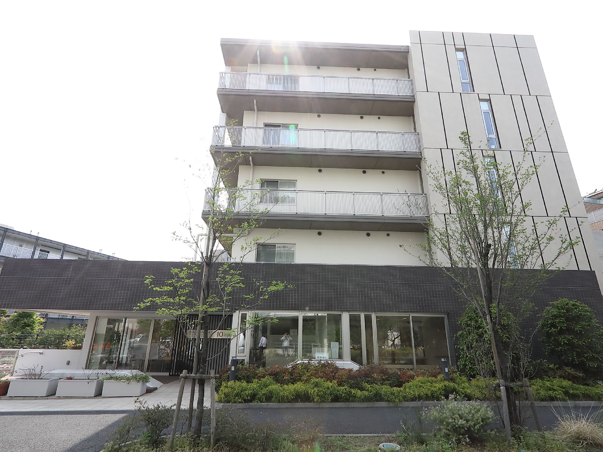 生垣で飾られた五階建てマンション型のグループホーム外観