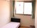 エアコン付きの部屋には大きな窓が付き、カーテンも設置されている。壁にはエアコンがあり、寝具のないベッドも置かれている。