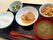 肉料理や豆料理、野菜の和え物、汁物、白いご飯が並べられているトレーにはスプーンと箸が置かれている。