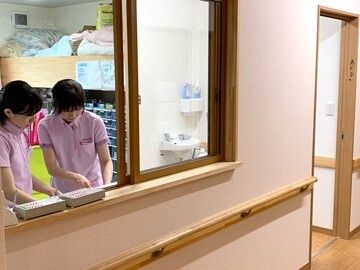 ピンクのポロシャツを着た女性スタッフが２名スタッフステーション内で話している様子。