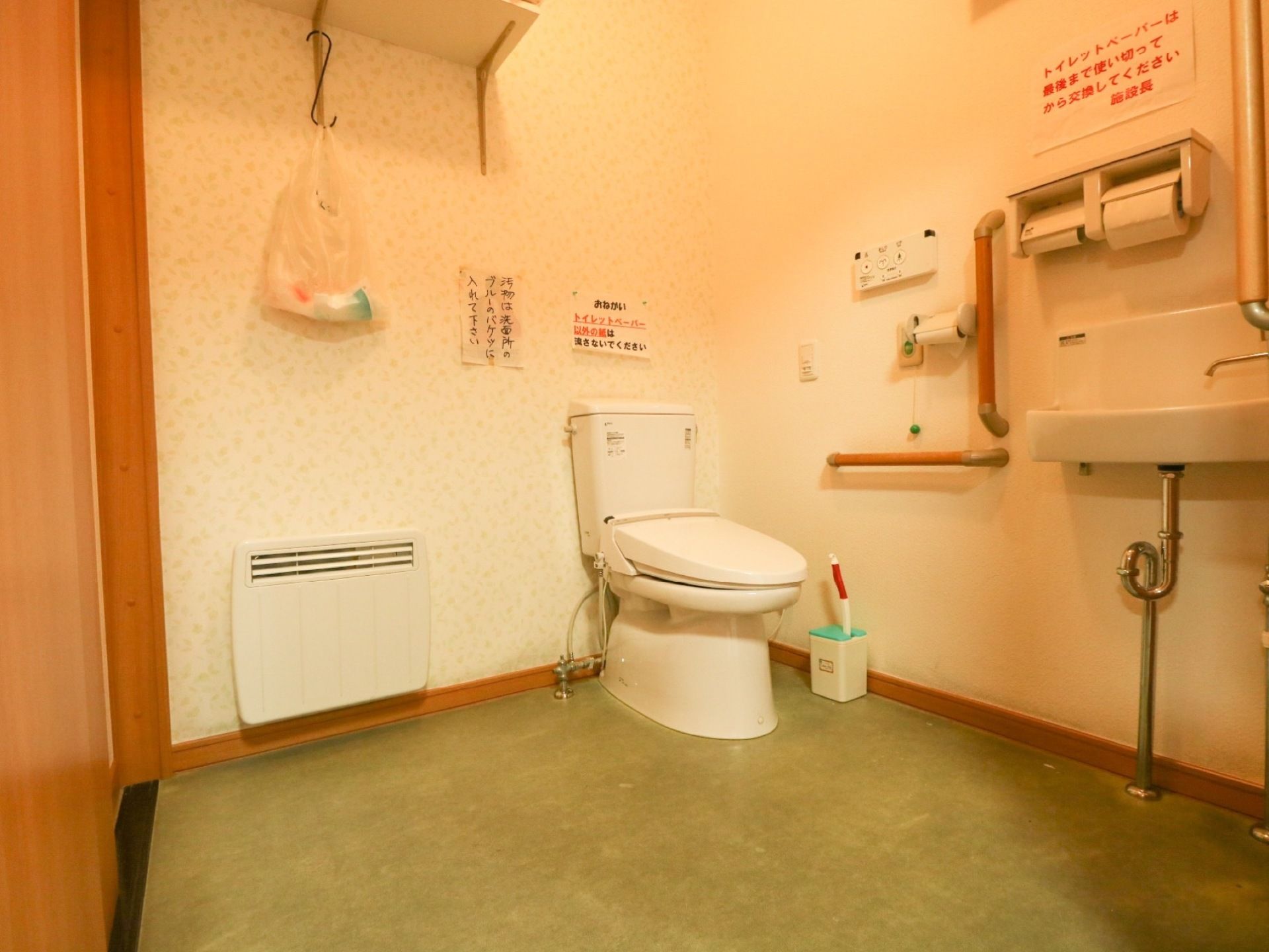 スペースが確保されたトイレには、温水洗浄便座器が完備されている。壁には、手すりが縦横にL字型に設置されている。