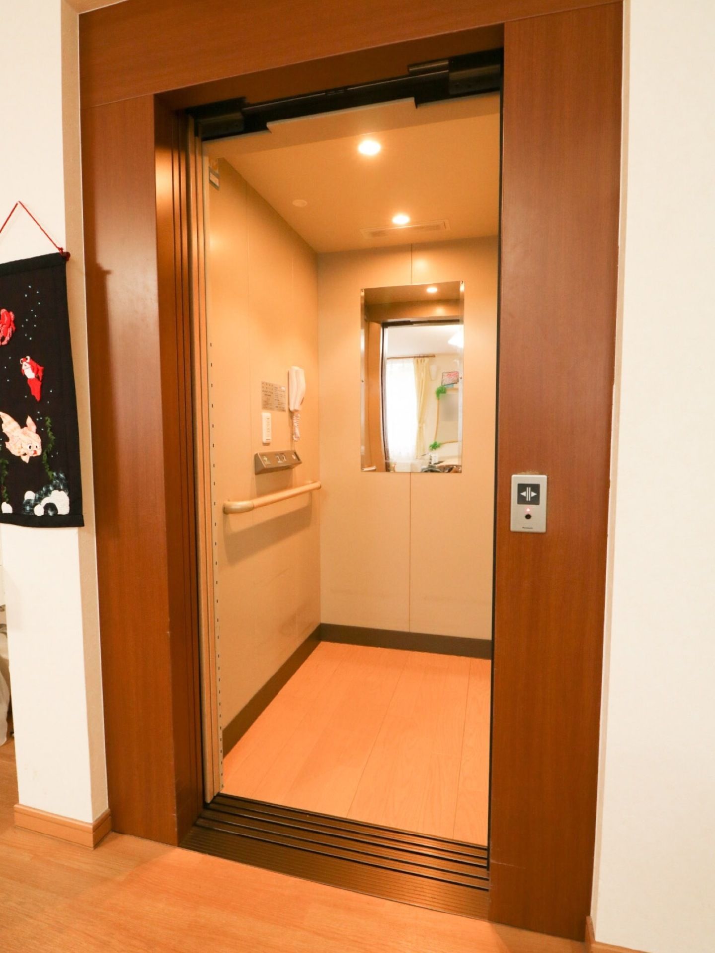 施設内に完備されているエレベーターの扉は開かれている。庫内には鏡やインターホン、手すりがある。