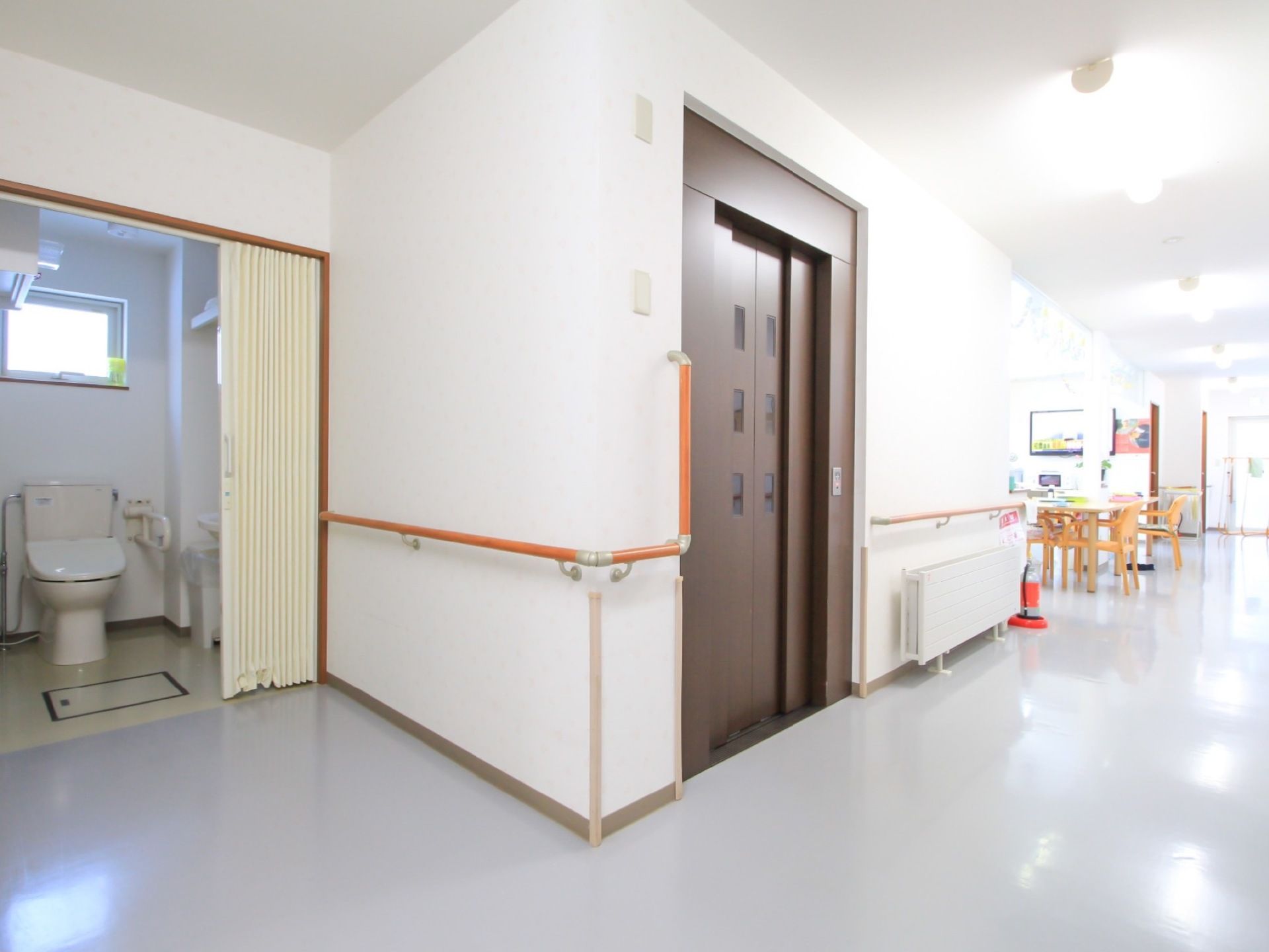 白色の壁や天井、床面のきれいな廊下である。エレベーターを降りてすぐの所に休憩スペースが設けられている。