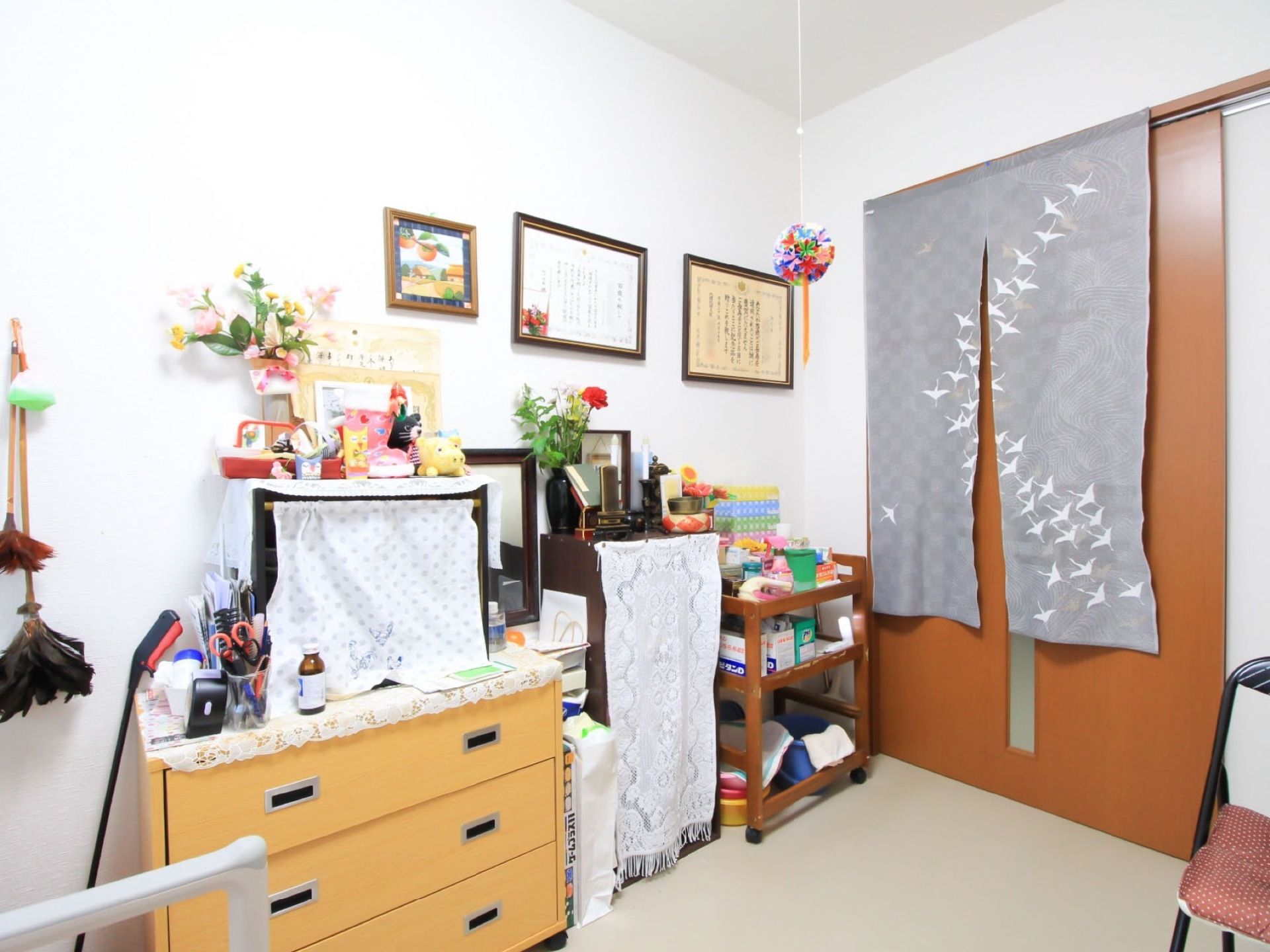 居室入口扉は縦方向にスリットガラスが入っている引き戸である。室内側にのれんがかかっている。表彰状が壁に飾られている。