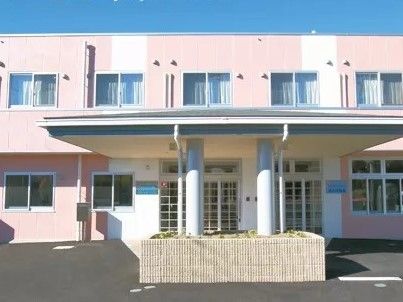 やわらかい色合いのあたたかみのある建物の外観。雨除け用のひさしがあるエントランス