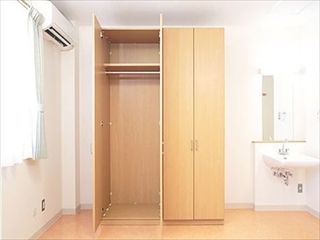 エアコンと収納設備、洗面台がついている施設内の居室の様子。左側に窓がついている部屋の様子