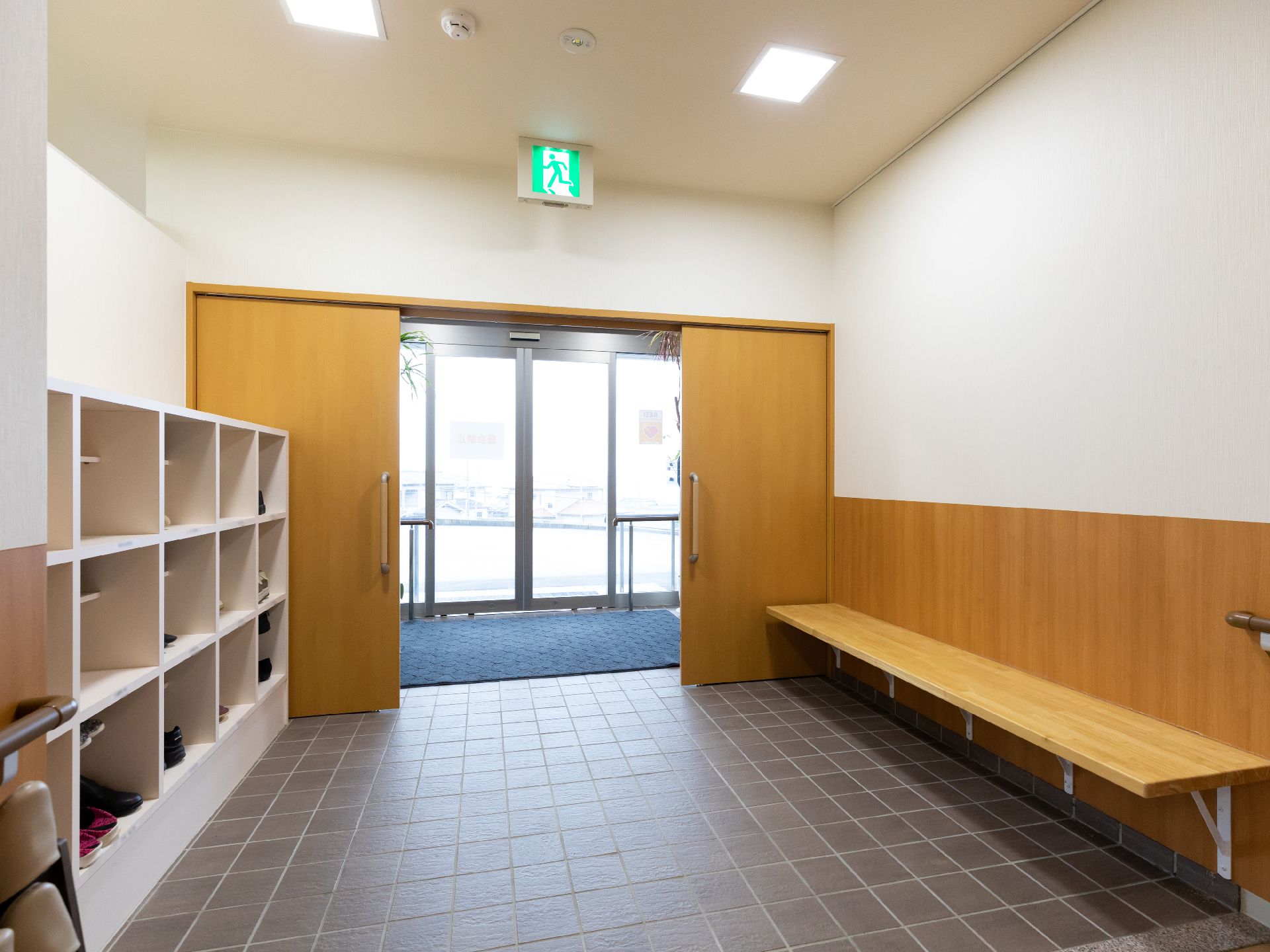 高齢者の方にタオルをかけてマッサージしているスタッフと振り返りながら会話する女性の様子