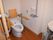 背もたれや手すりが設置されたトイレには引き戸が付き、壁にはオレンジの呼び出しボタンもある。