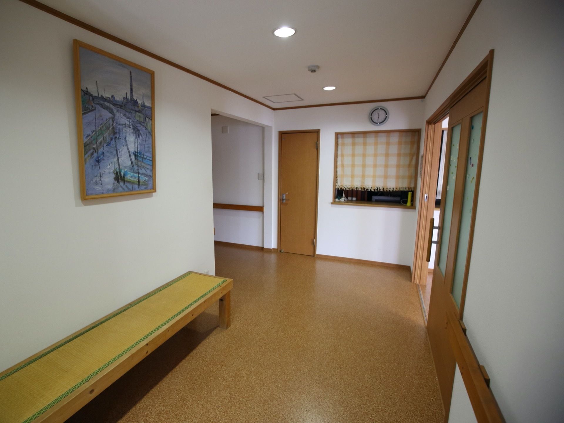 左側の壁に大きな絵画が飾ってある。その下には畳ベンチが設置されている。正面のカウンターにカーテンが掛けられている。