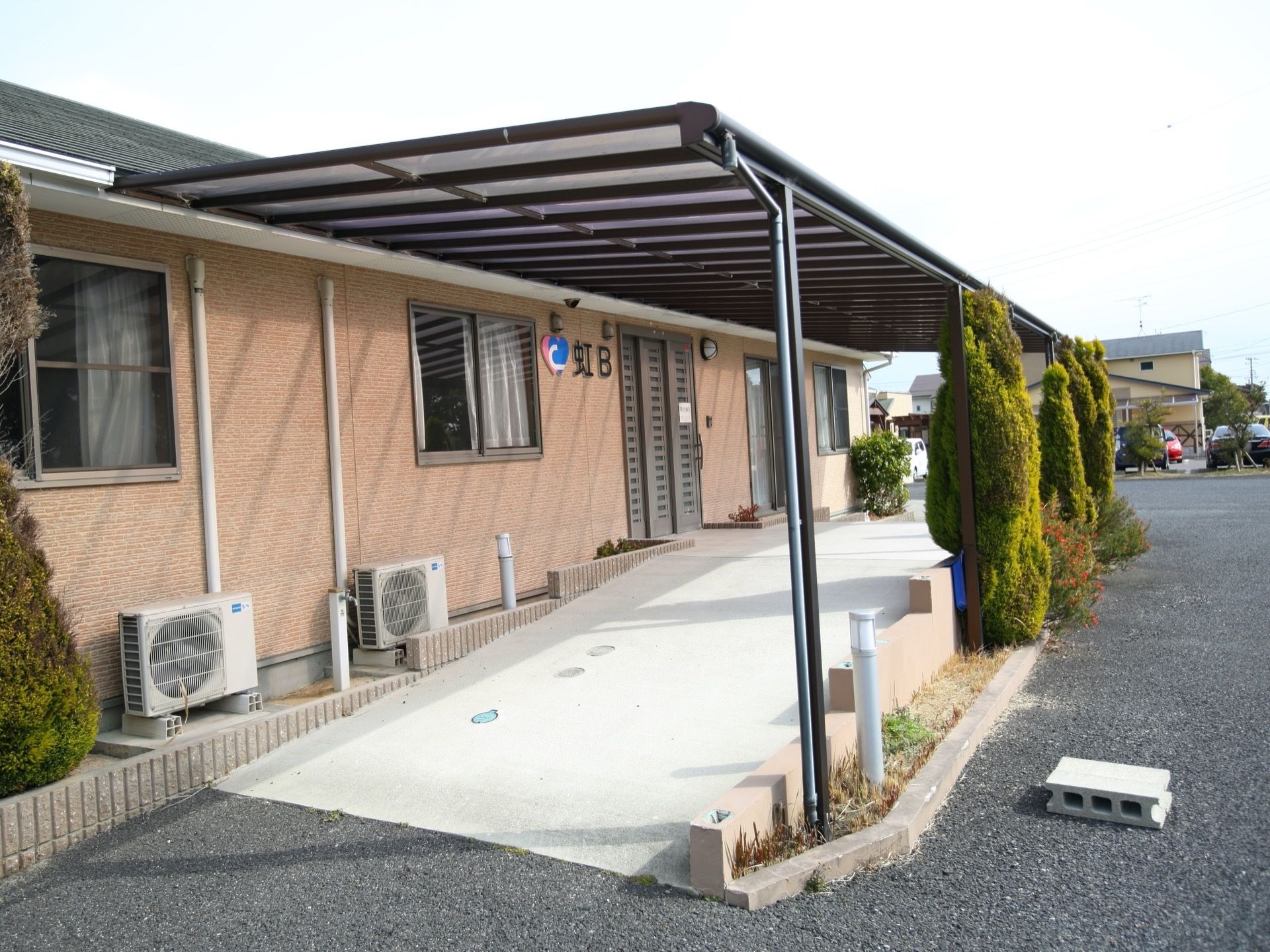 平屋造りの建物である。玄関扉の横の壁には施設名が取り付けられており、外灯もある。玄関前には屋根が設置されている。