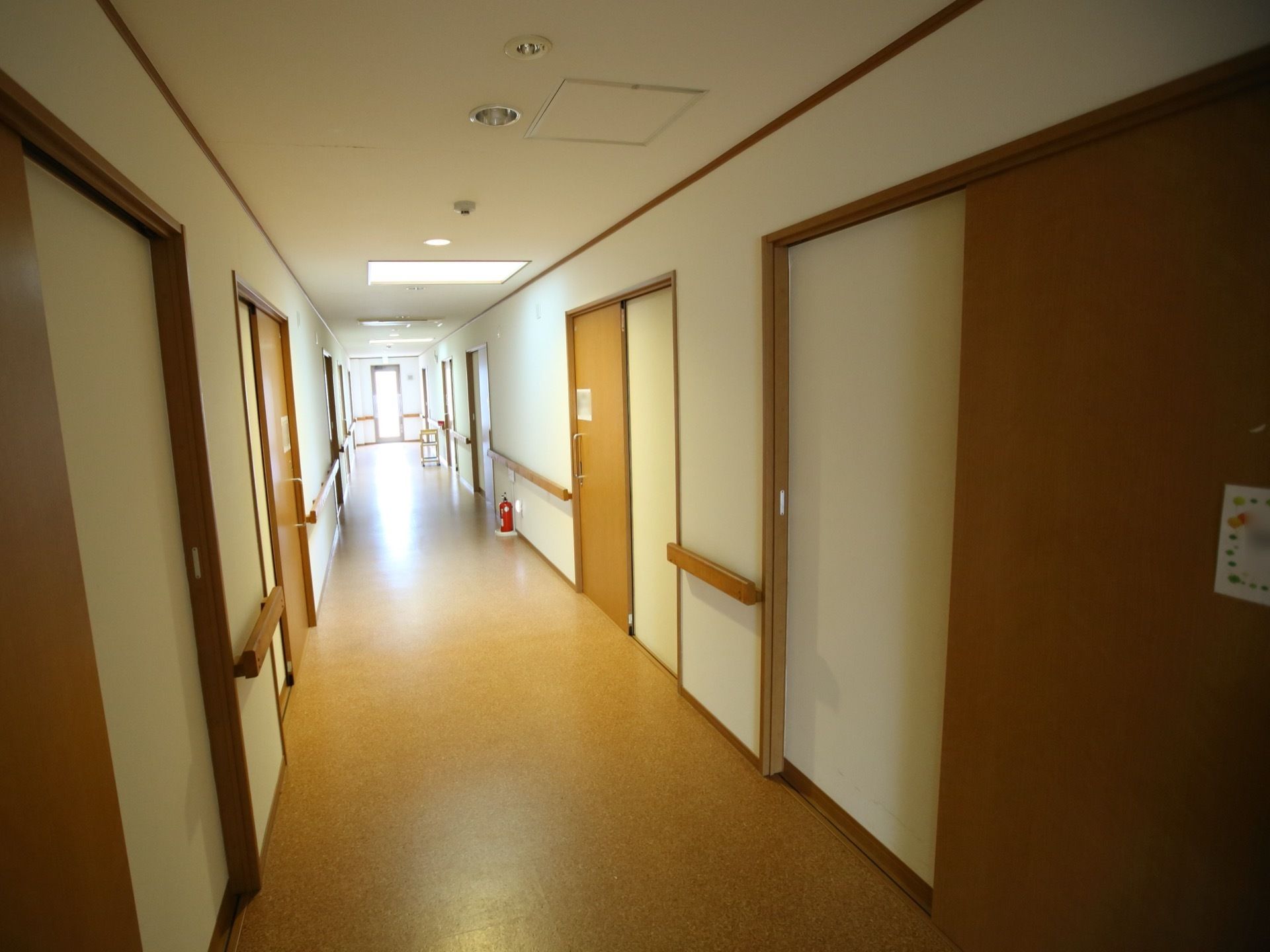 奥の方に向かって、まっすぐに伸びる通路である。突き当たりには扉があり、途中の床には消火器が１本置かれている。