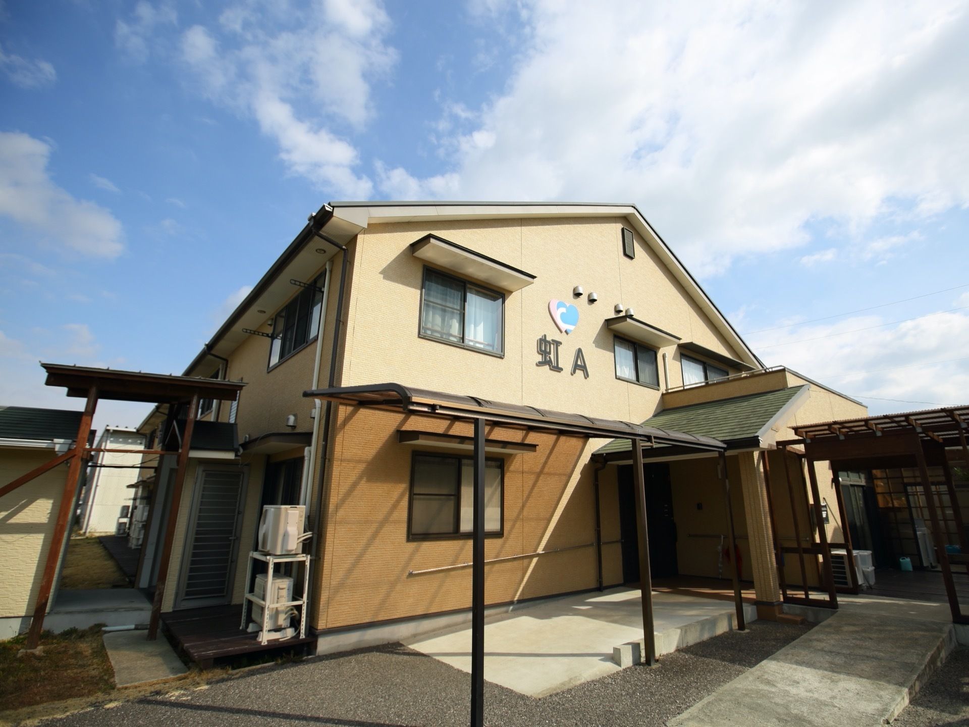 施設は、住宅街に馴染みやすい一般的な戸建てのような造りである。スロープが外玄関へと続き、通路屋根が設置されている。