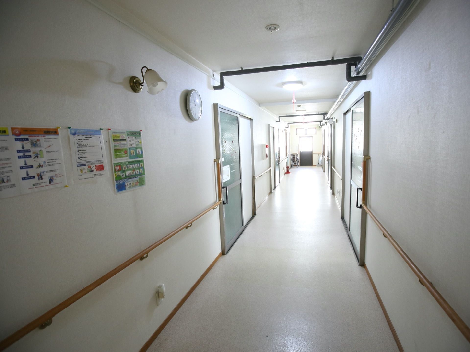 真っ直ぐ続く見通しの良い通路である。両サイドの壁に手すりがあり、居室の扉近くにはＩ字型の手すりが設置され、居室への出入りがしやすい。