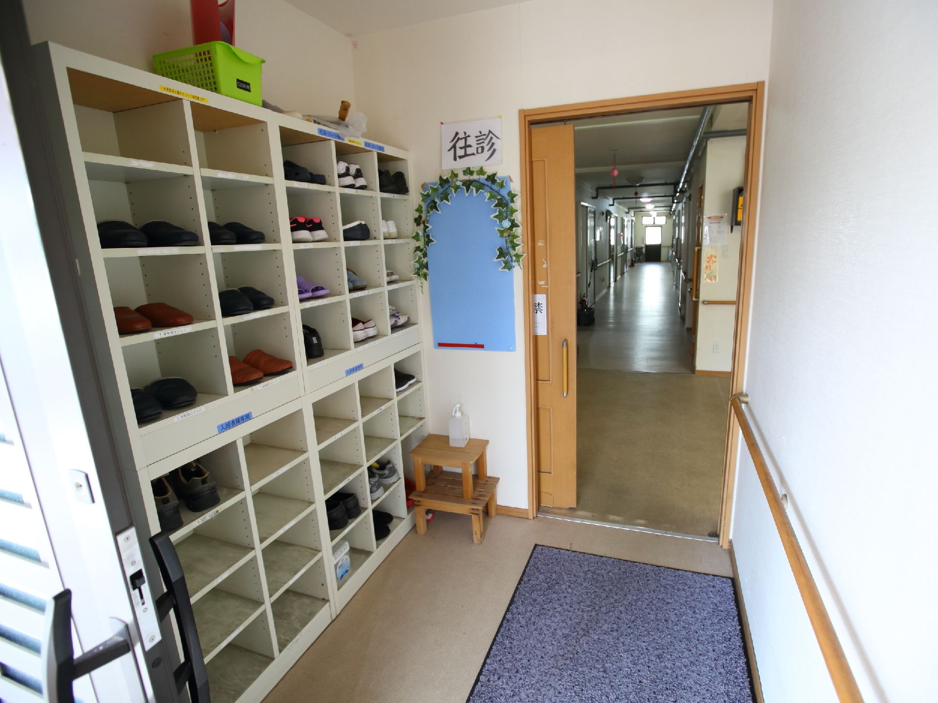 消毒液が置かれた、入居者の靴を入れる下駄箱がある玄関