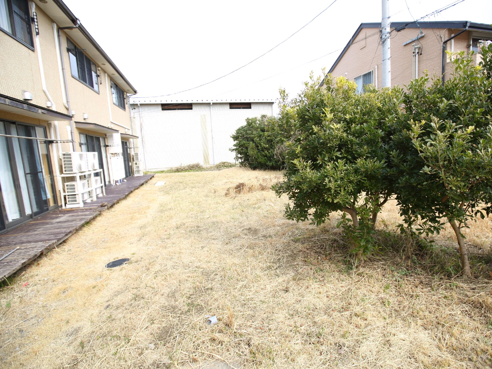 二階建て住宅型施設の外に広がっている、木が植えられた庭