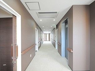 手すりがついた幅広の廊下の様子。両側の壁に個室のドアがある