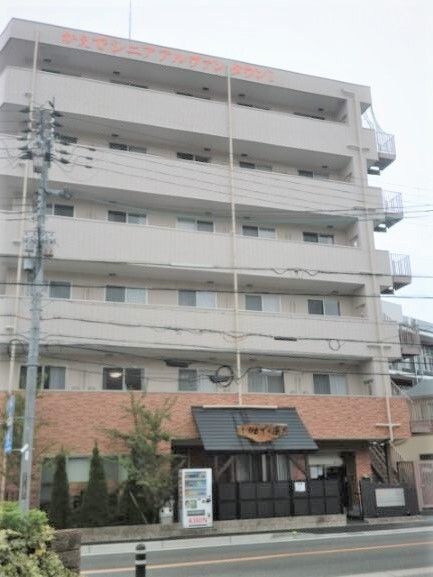 高齢者2名とスタッフが手を握りながら談笑している様子。施設内の会話の一画面