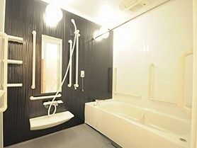車いすにのる男性とそれを押している女性スタッフ。両側に自然が広がる遊歩道の写真