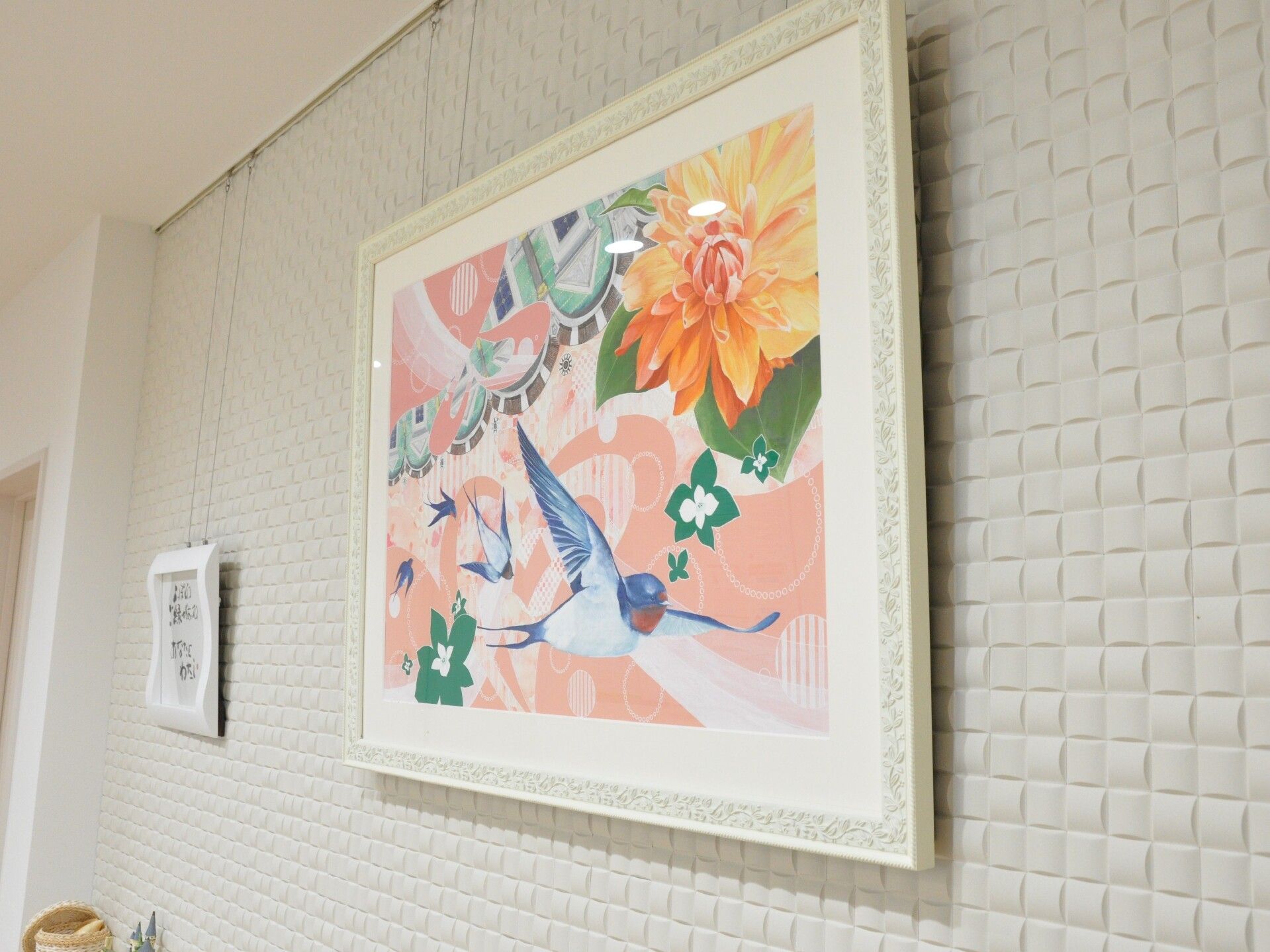 大きなオレンジのダリアが右上に描かれ、数匹の燕が飛んでいる様子が描かれた絵画。背景がピンクで明るい雰囲気。