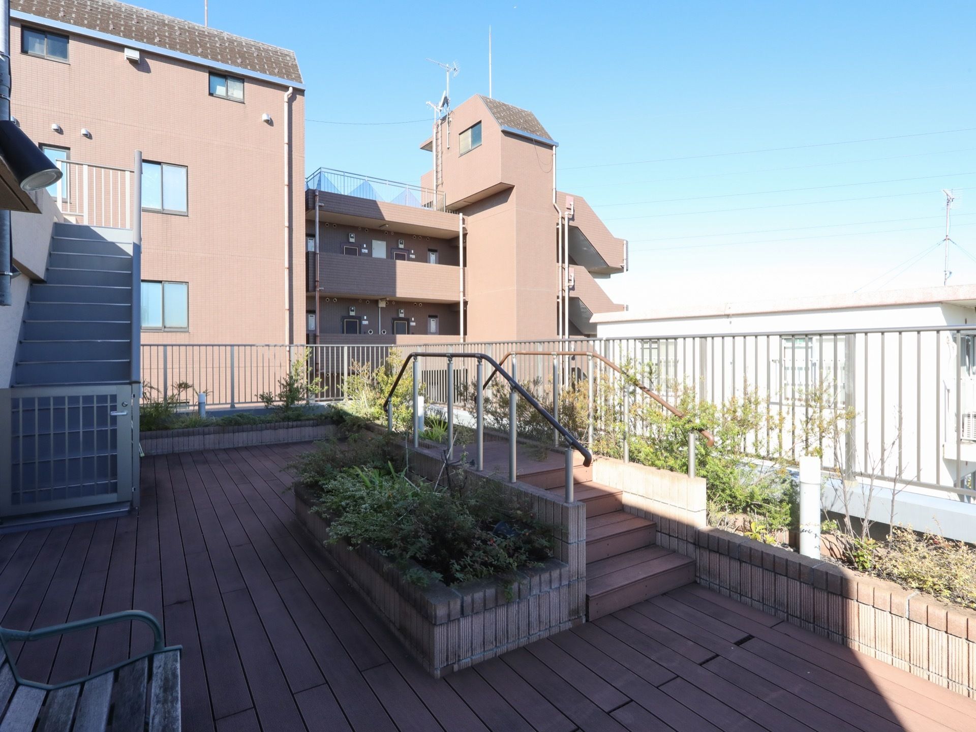 屋上庭園がある。フェンス沿いに花壇があり、いろいろな木や草花が植えられている。手すりがついた階段も設置されている。