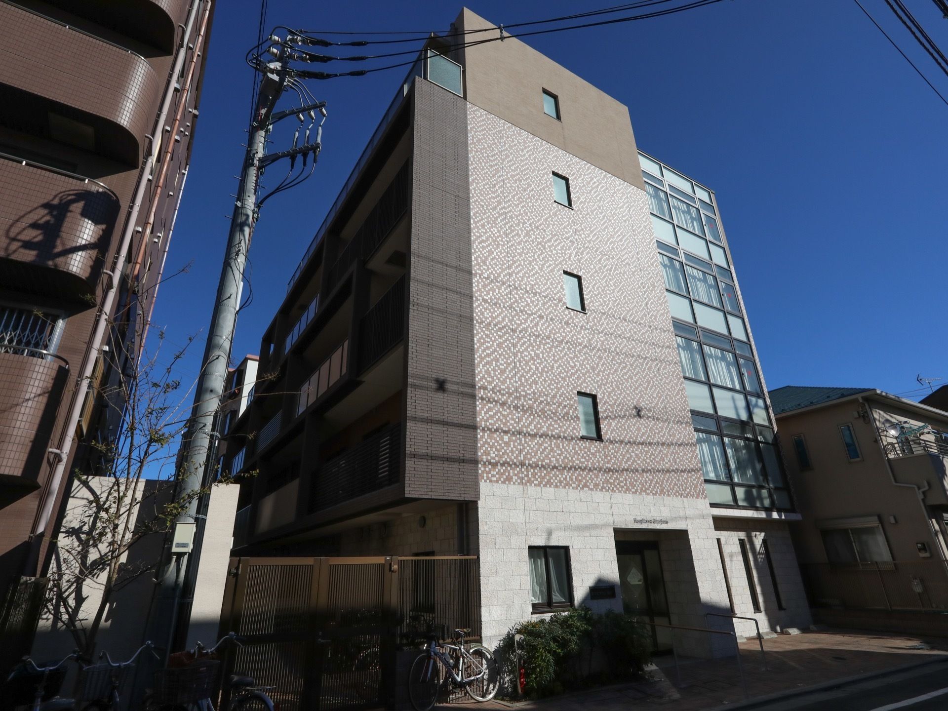 道路に面した敷地に建っている５階建ての姿勢である。道路沿いの敷地内に駐輪スペースがあり、自転車が何台か置かれている。