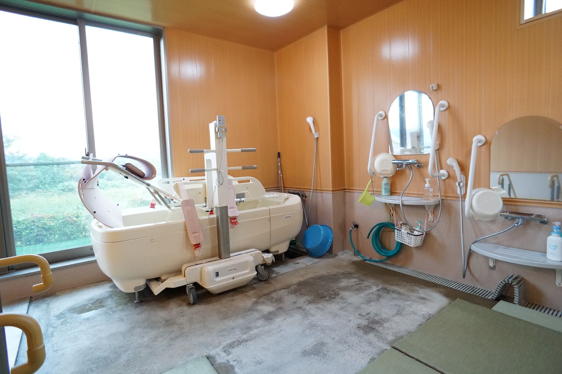 カメラに向かって笑顔を見せるスタッフと高齢者の女性。施設での何気ない一場面の様子