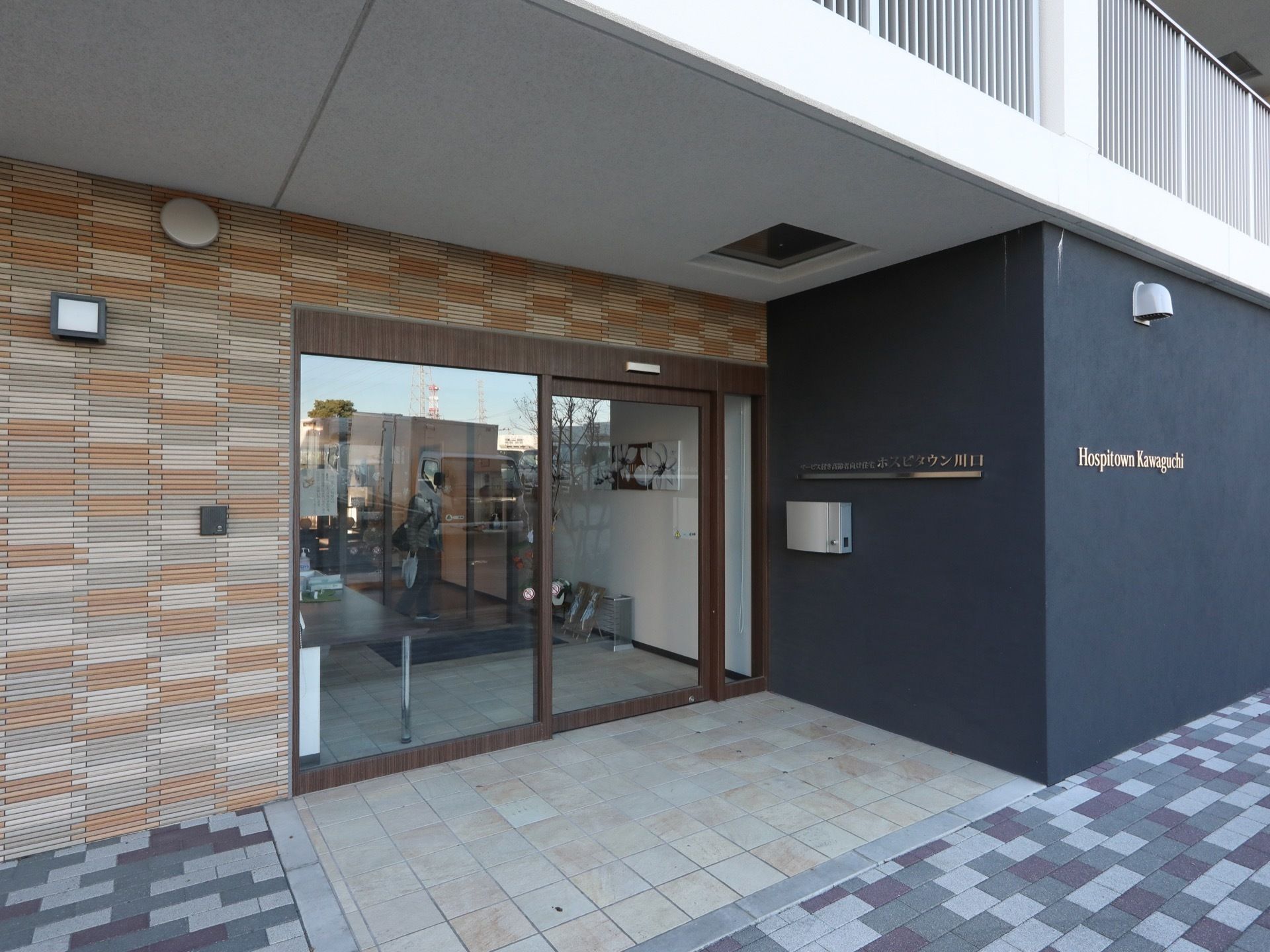 落ち着いたカラーにデザインされたエントランスである。床面は段差がなく、フラット造りになっている。外灯も設置されている。