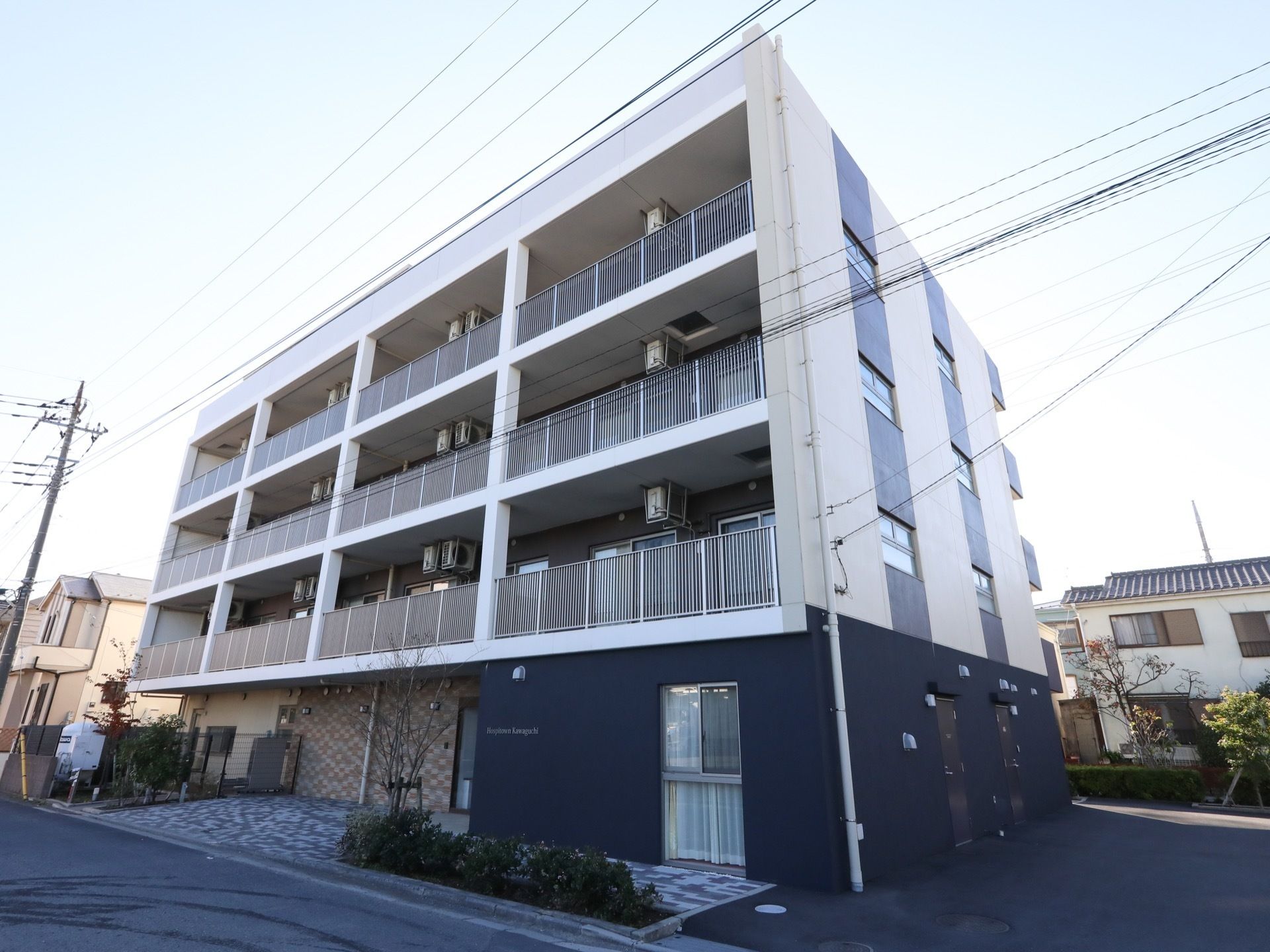 住宅街に立地する、施設である。各居室にバルコニーがある。敷地に庭木が植えられている。目の前は道路である。
