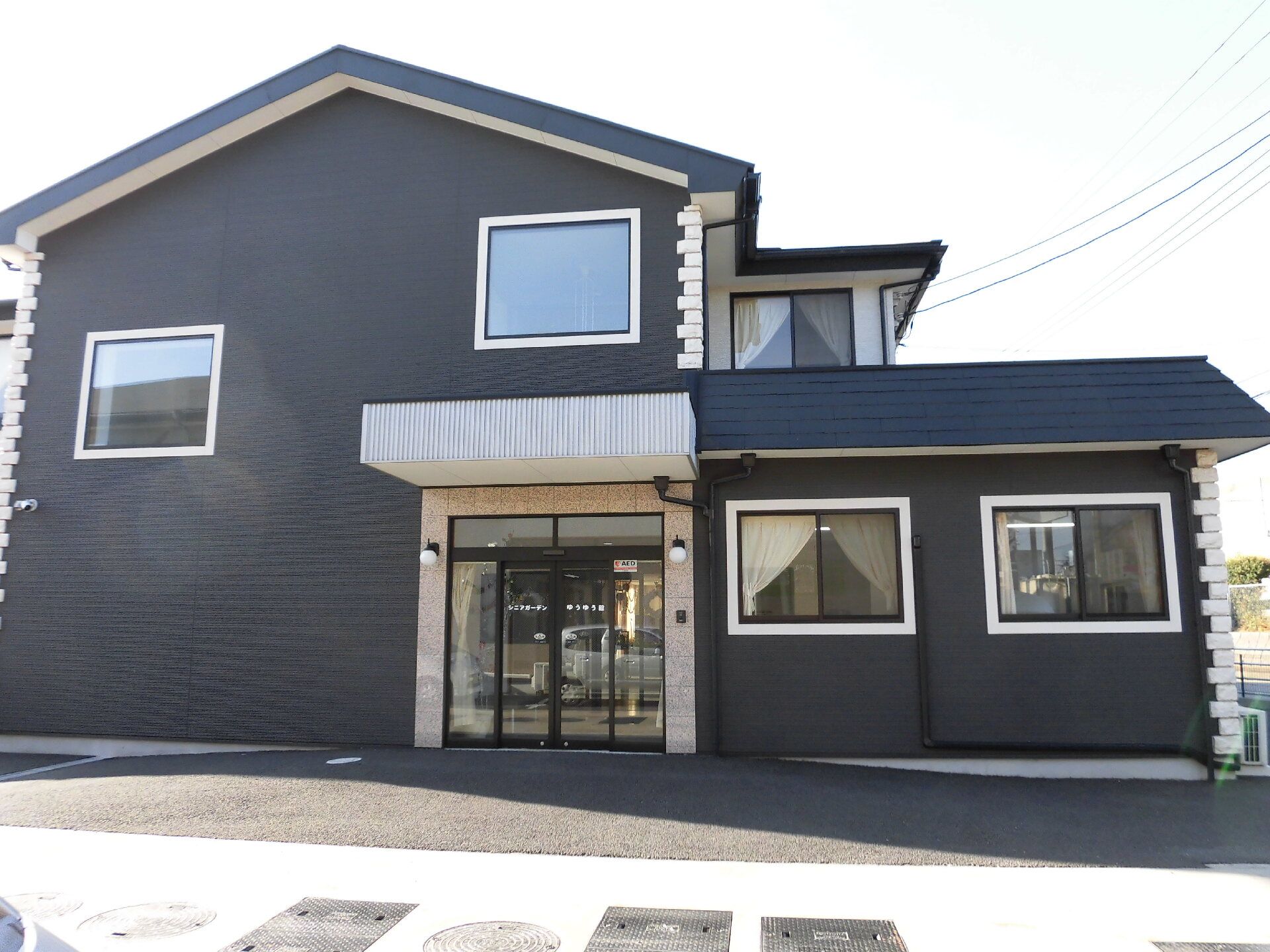 三角屋根が付いた2階建ての建物。自動ドアが設置された玄関には屋根も付いている。