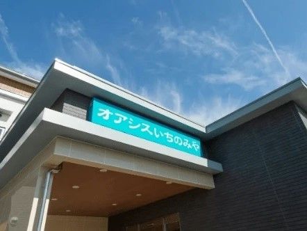 大きなグリーンの看板に白い文字で住宅名が書かれた屋根が玄関に付いている。