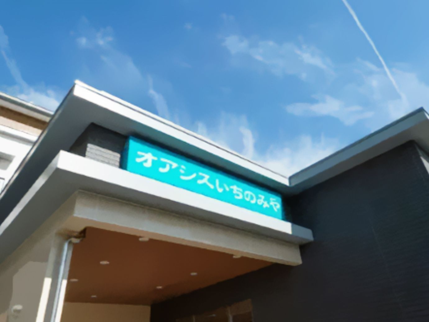 大きなグリーンの看板に白い文字で住宅名が書かれた屋根が玄関に付いている。