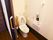 温水洗浄便座器が完備されているトイレである。白い壁には、手すりや緊急呼び出しブザーが設置されている。