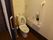 温水洗浄便座器が完備されているトイレである。白い壁には、手すりや緊急呼び出しブザーが設置されている。
