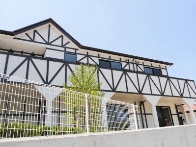 ヨーロッパのロッジ風の建物は2階建て。周辺には緑やフェンスもある。