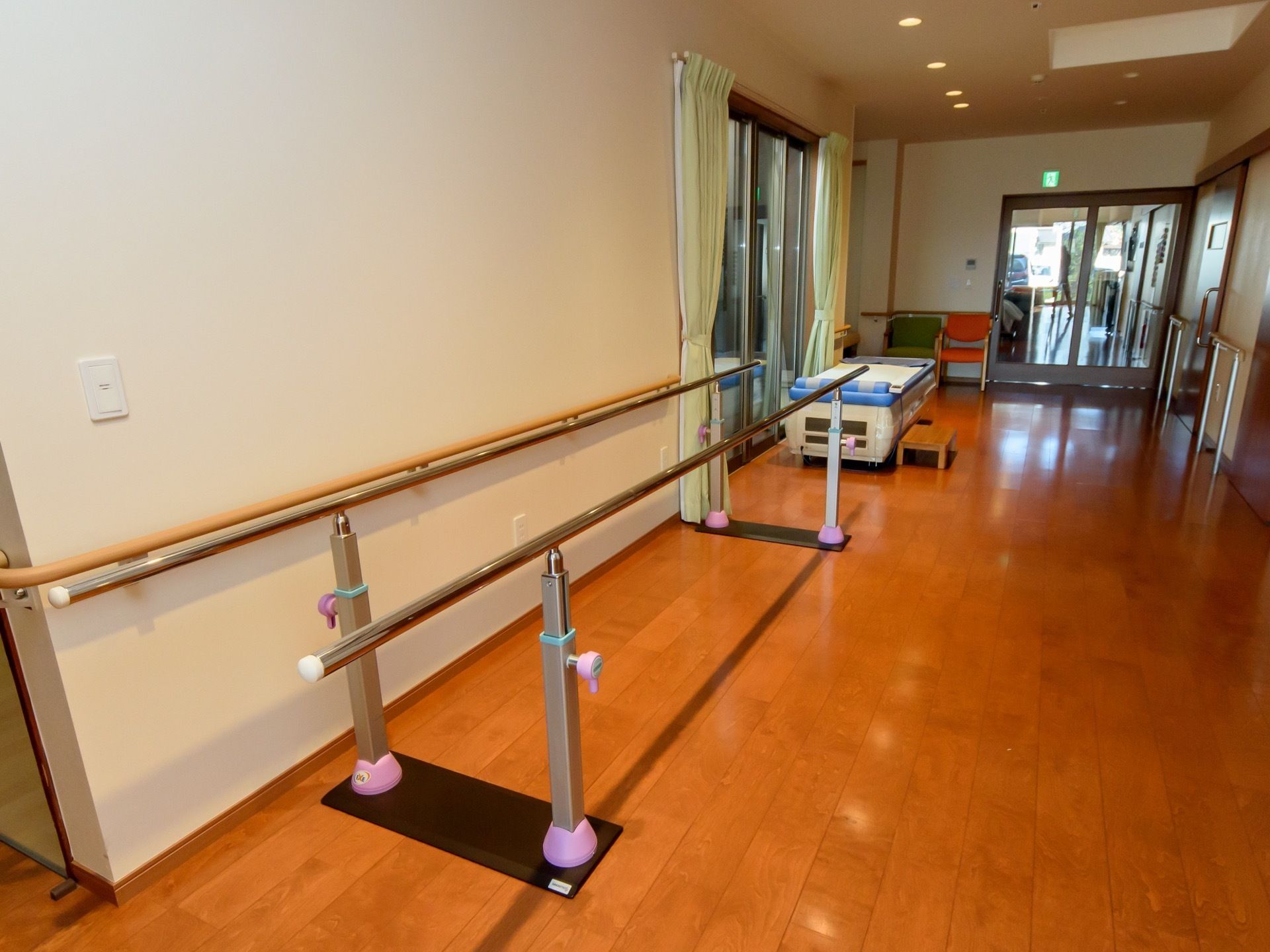 広々とした室内には、壁に寄せるように平行棒が配置されている。奥にはマッサージ台もあり、専門スタッフによる施術が受けられる。