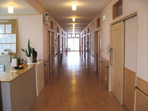 施設内の広めの廊下の様子。個室のドアと壁についた手すりが映っている様子