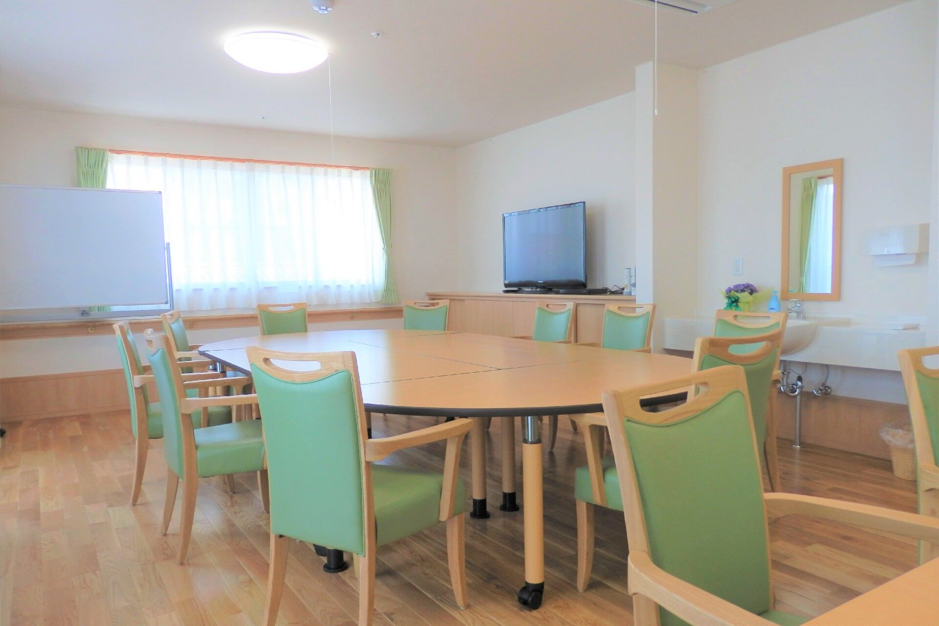 フローリングの部屋にベッドが置かれている。奥のほうに洗面台とトイレがある