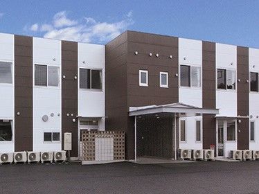 ２階建ての建物はブラウンと白でまとめられ、玄関部分には屋根もついている。