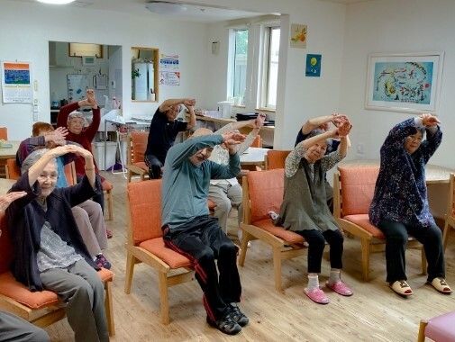 福祉車両から下りようとしている眼鏡をかけた高齢男性のサポートに当たっている若いスタッフ。