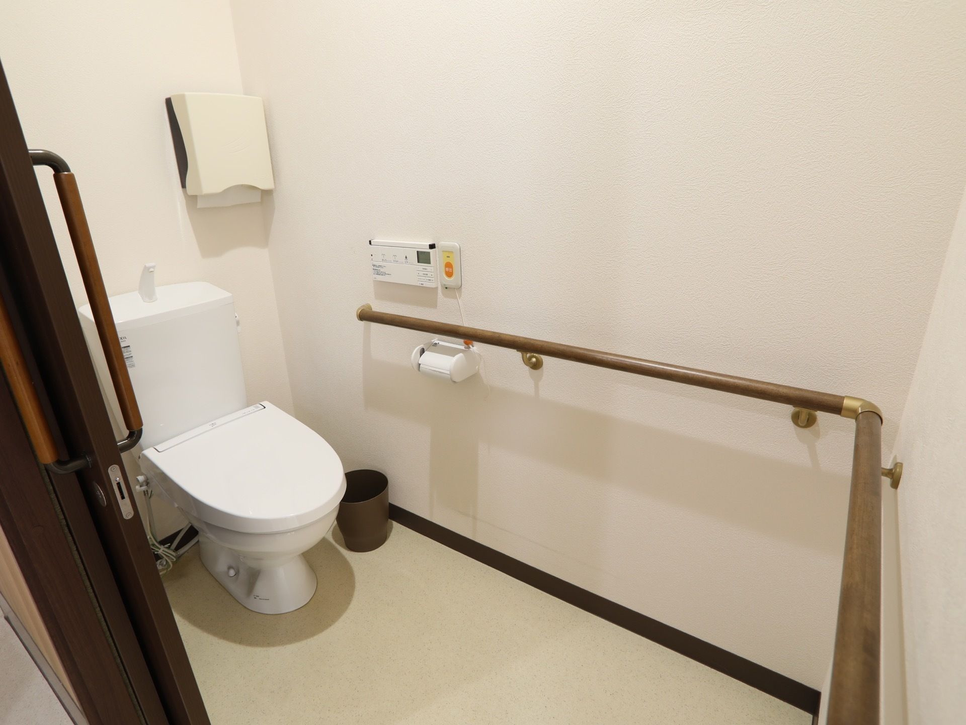 出入口から便座横まで、伝え歩きができるように手すりを完備している。便器の後の角にハンドべーパーを設置している。
