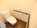 清潔感のあるトイレである。壁には木製の手すりが取り付けられているほか、緊急時の呼び出しボタンがある。