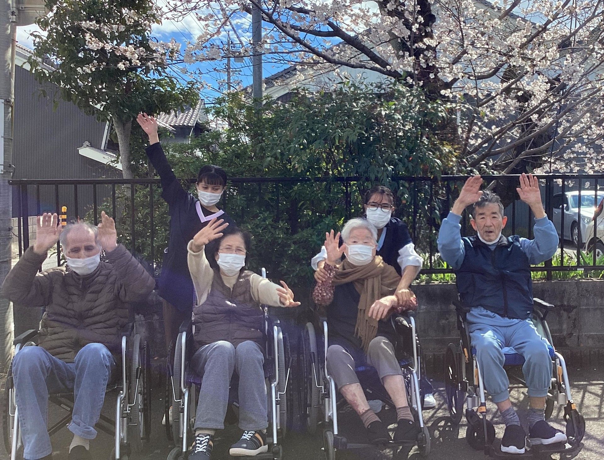 桜の下で手を振る人々