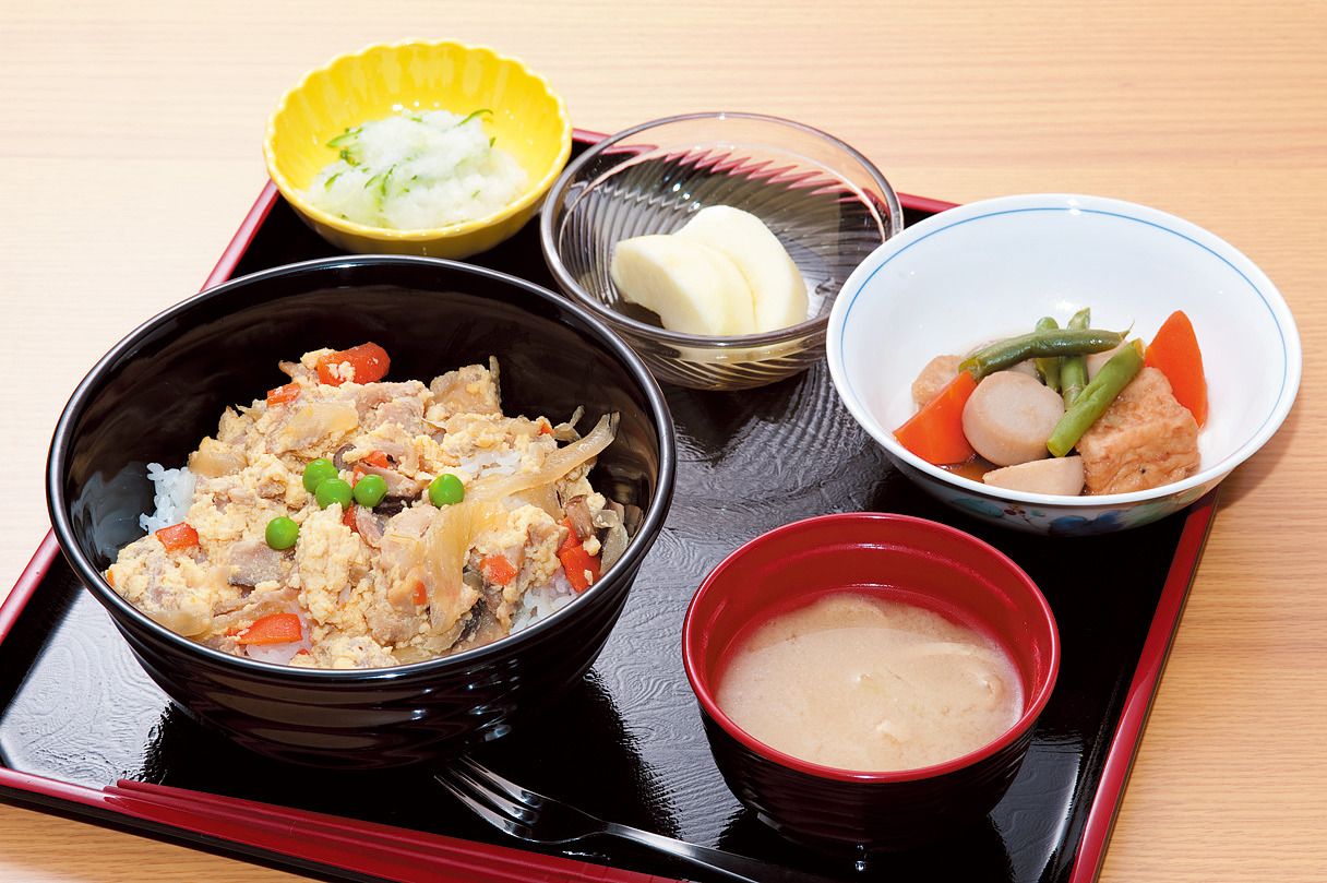親子丼と、野菜の煮物と味噌汁、リンゴのデザートが付いたメニュー