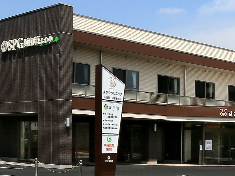 ブラウン系の外壁の２階建ての建物の玄関には自動ドアが設置され、館銘板が建っている。